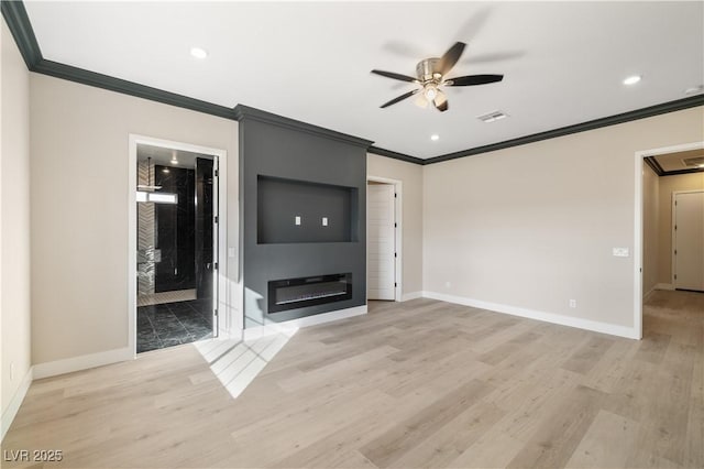 unfurnished living room with crown molding, a large fireplace, ceiling fan, and light wood-type flooring