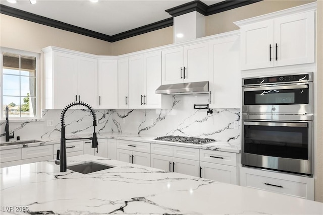 kitchen featuring double oven, light stone counters, gas stovetop, ornamental molding, and white cabinets