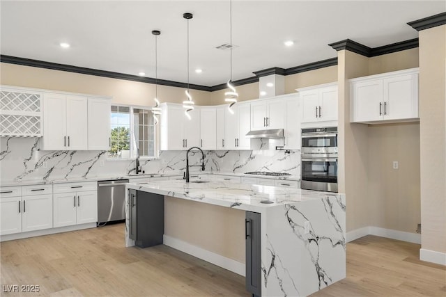 kitchen with a kitchen island with sink, pendant lighting, stainless steel appliances, and white cabinets