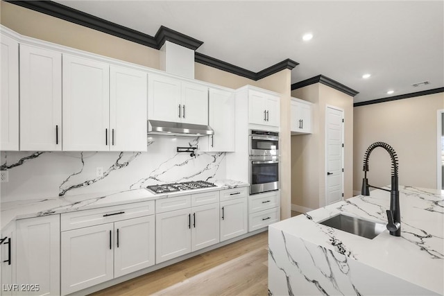 kitchen featuring light stone counters, sink, and white cabinets