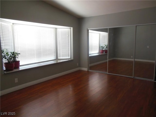 unfurnished bedroom with lofted ceiling, dark hardwood / wood-style flooring, and a closet