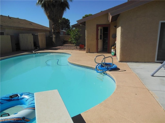 view of swimming pool featuring a patio area and a diving board