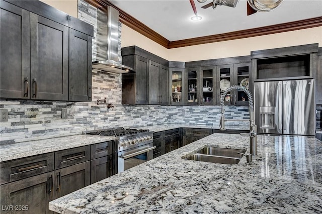 kitchen featuring tasteful backsplash, ornamental molding, appliances with stainless steel finishes, light stone countertops, and wall chimney range hood