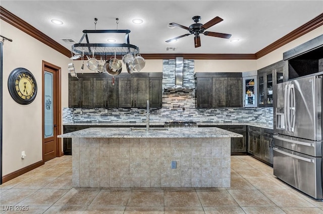 kitchen featuring sink, a kitchen island with sink, dark brown cabinetry, stainless steel fridge with ice dispenser, and light stone countertops