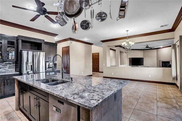 kitchen with sink, a kitchen island with sink, stainless steel appliances, light stone counters, and light tile patterned flooring