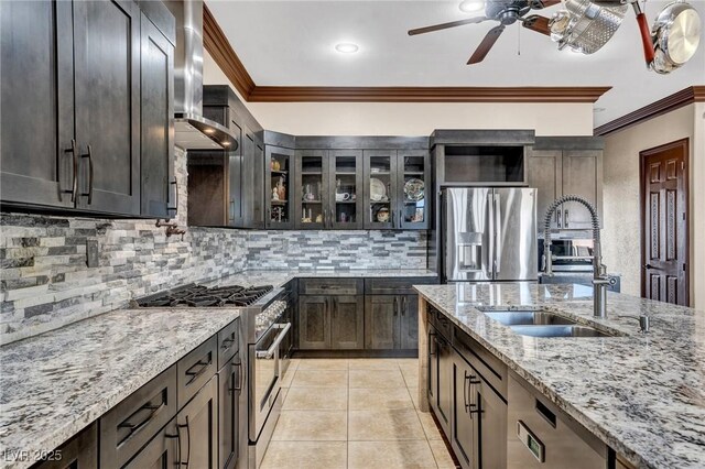 kitchen with appliances with stainless steel finishes, ornamental molding, light tile patterned floors, light stone counters, and wall chimney exhaust hood