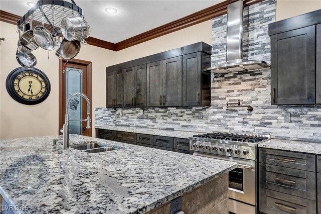 kitchen with sink, high end stainless steel range, light stone counters, and wall chimney exhaust hood