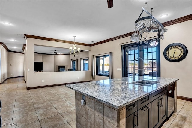 kitchen featuring sink, light tile patterned floors, a kitchen island with sink, light stone countertops, and ceiling fan with notable chandelier