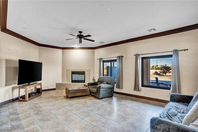 tiled living room with crown molding, ceiling fan, and a tile fireplace