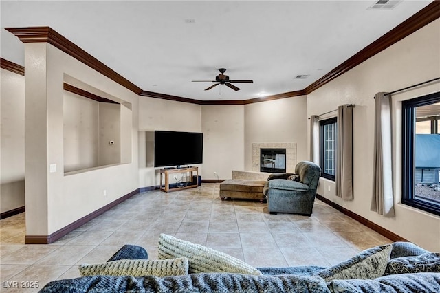 living room featuring light tile patterned floors, a fireplace, ornamental molding, and ceiling fan