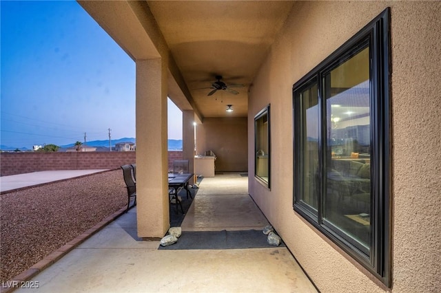 patio terrace at dusk featuring ceiling fan