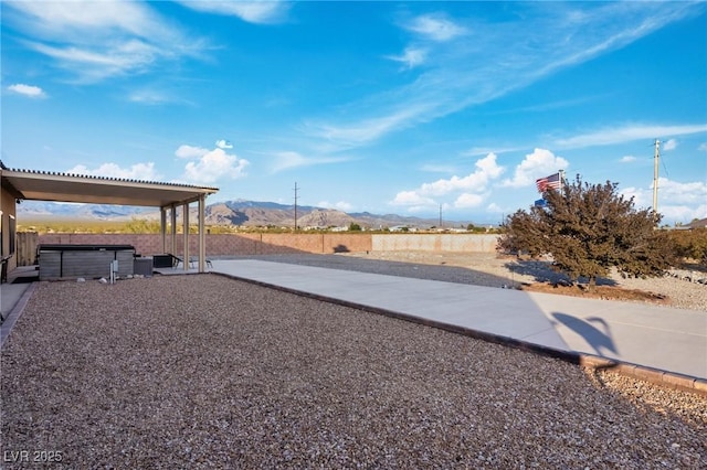 view of yard featuring a hot tub, a mountain view, and a patio area