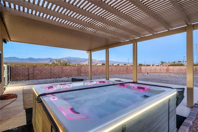 view of patio / terrace with a hot tub, a mountain view, and a pergola