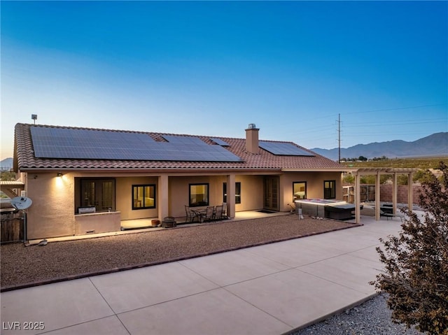 rear view of property featuring a hot tub, a pergola, a patio area, and a mountain view