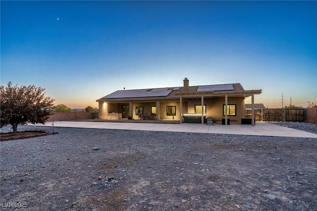 back house at dusk with a patio area and solar panels