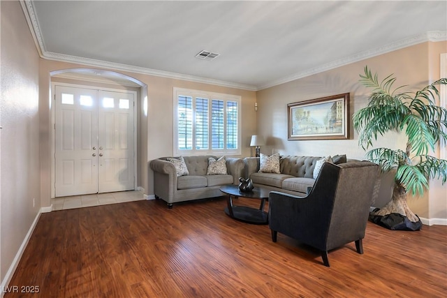 living room with baseboards, wood finished floors, visible vents, and crown molding