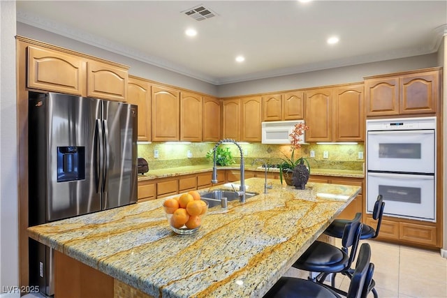 kitchen featuring tasteful backsplash, white appliances, light tile patterned flooring, and a sink