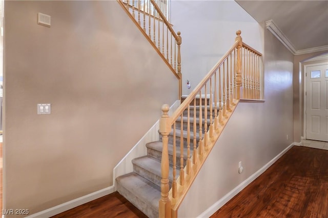 stairs with ornamental molding and hardwood / wood-style floors