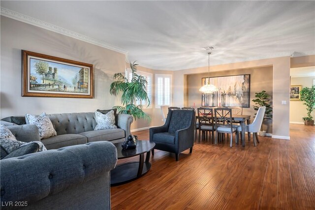 living room featuring crown molding, wood-type flooring, and an inviting chandelier