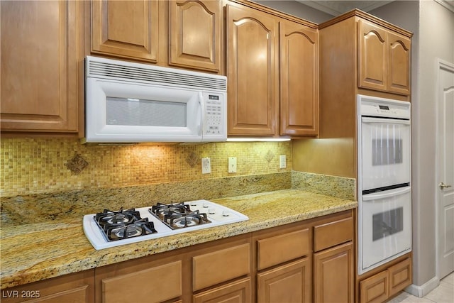 kitchen with tasteful backsplash, white appliances, and light stone countertops