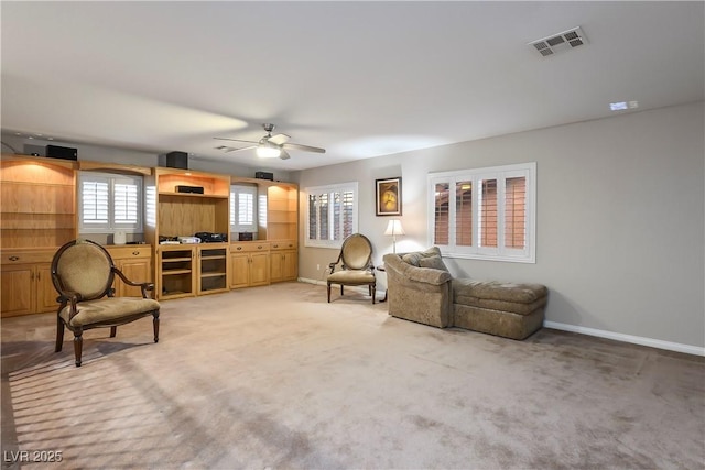 sitting room featuring baseboards, a ceiling fan, visible vents, and light colored carpet