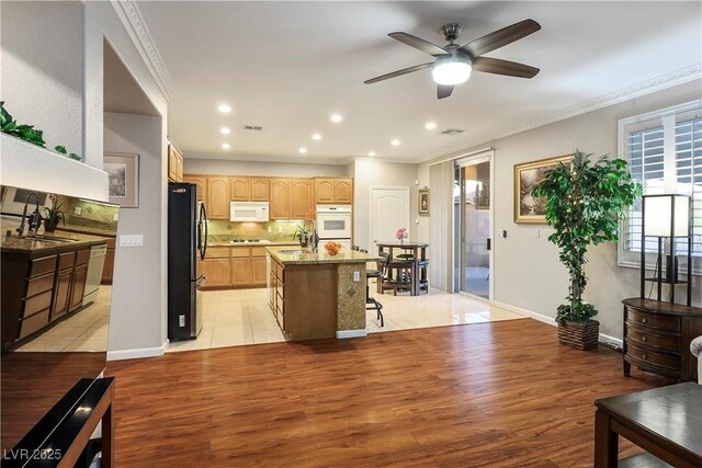 kitchen with a kitchen island, sink, decorative backsplash, ornamental molding, and white appliances