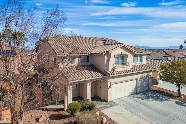 mediterranean / spanish house with concrete driveway, a tile roof, and stucco siding