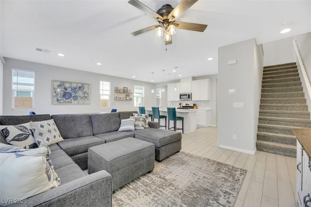 living room with light hardwood / wood-style flooring, a wealth of natural light, and ceiling fan