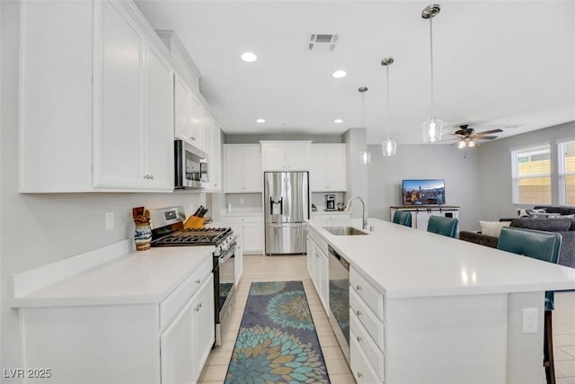 kitchen with pendant lighting, white cabinetry, sink, a large island with sink, and stainless steel appliances