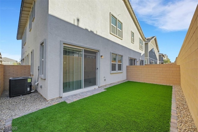 rear view of house with central AC unit and a yard