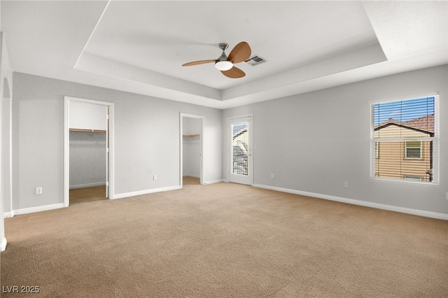 unfurnished bedroom featuring a tray ceiling, light carpet, and multiple windows