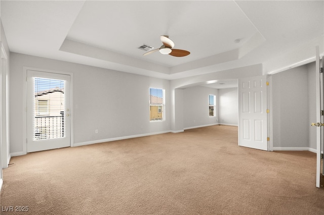 unfurnished room with light carpet, plenty of natural light, a raised ceiling, and ceiling fan