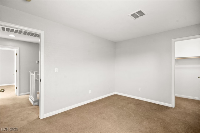 unfurnished bedroom featuring a walk in closet, light colored carpet, and a closet