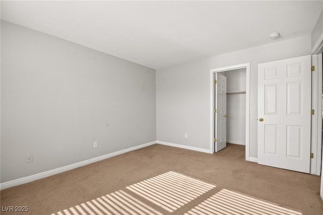 unfurnished bedroom featuring light colored carpet, a spacious closet, and a closet