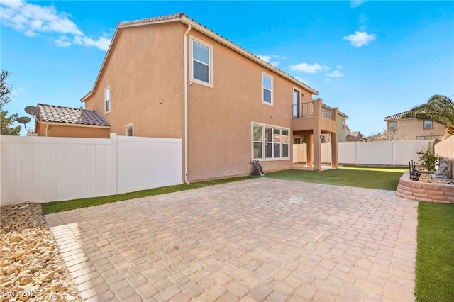 back of property featuring a balcony and a patio area