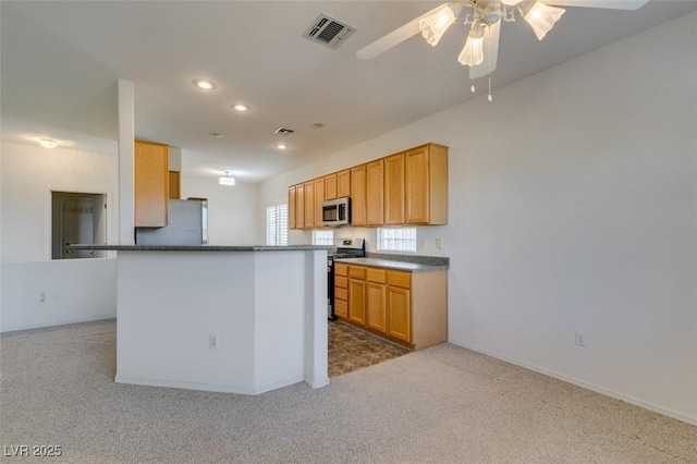 kitchen featuring light brown cabinetry, appliances with stainless steel finishes, kitchen peninsula, carpet floors, and ceiling fan