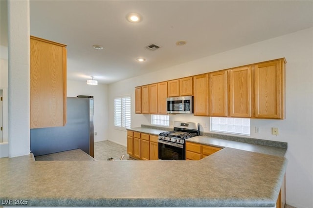 kitchen with light brown cabinetry, stainless steel appliances, and kitchen peninsula