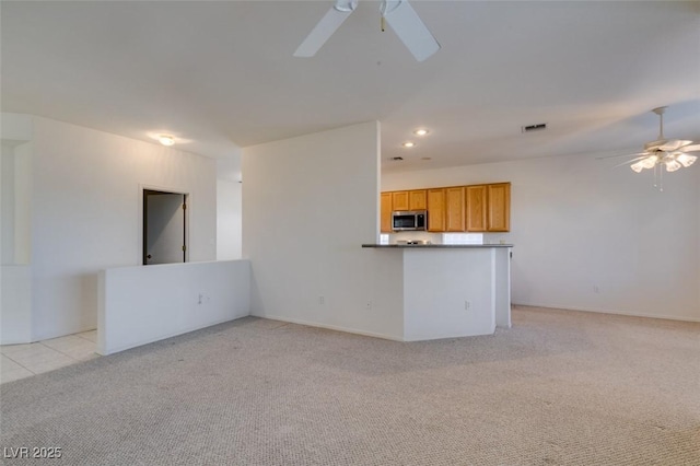 unfurnished living room with light carpet and ceiling fan