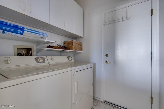 clothes washing area featuring cabinets, light tile patterned floors, and washing machine and clothes dryer