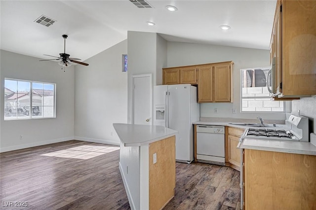 kitchen with white appliances, vaulted ceiling, a center island, and light wood-type flooring