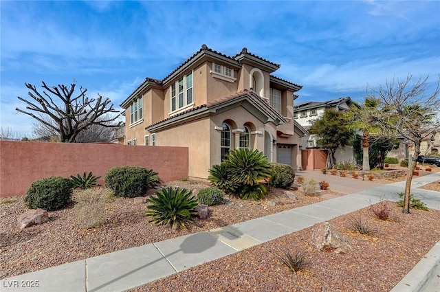 view of front of property with a tiled roof, fence, and stucco siding