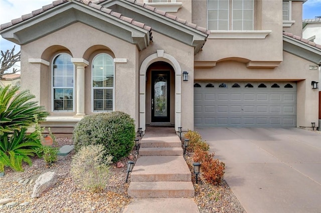 view of front of home with a garage, driveway, a tile roof, and stucco siding