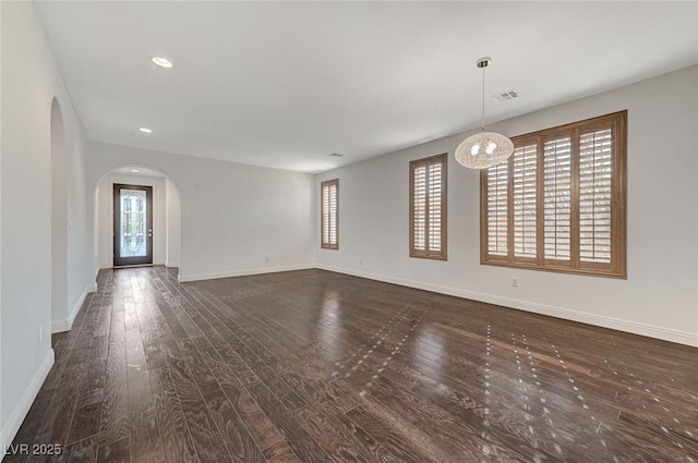 unfurnished living room featuring baseboards, visible vents, arched walkways, dark wood-style flooring, and recessed lighting