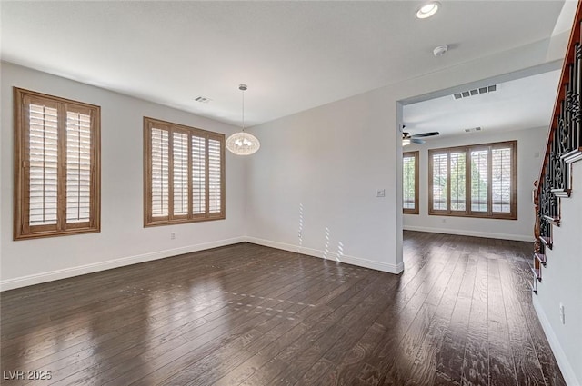 empty room featuring dark wood-type flooring and ceiling fan with notable chandelier