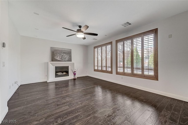 unfurnished living room with a fireplace, wood finished floors, a ceiling fan, visible vents, and baseboards