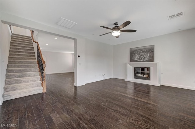 unfurnished living room featuring dark wood-type flooring and ceiling fan