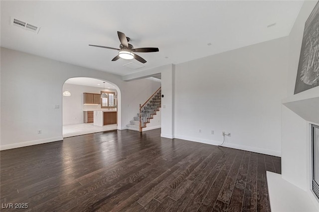 unfurnished living room featuring arched walkways, visible vents, stairway, and wood finished floors