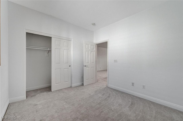 unfurnished bedroom with carpet, a closet, and baseboards