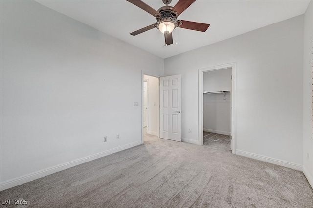 unfurnished bedroom with a spacious closet, light colored carpet, a closet, and ceiling fan