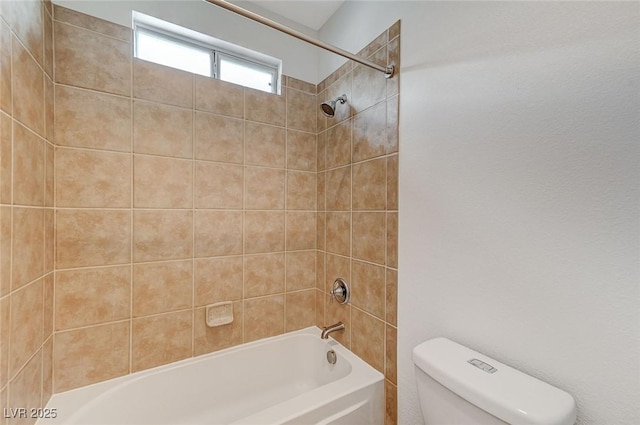 bathroom featuring tiled shower / bath and toilet